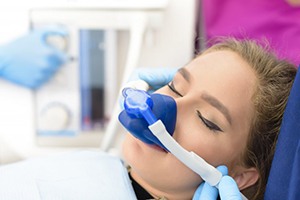 Young woman wearing blue nitrous oxide sedation dentistry mask over her nose